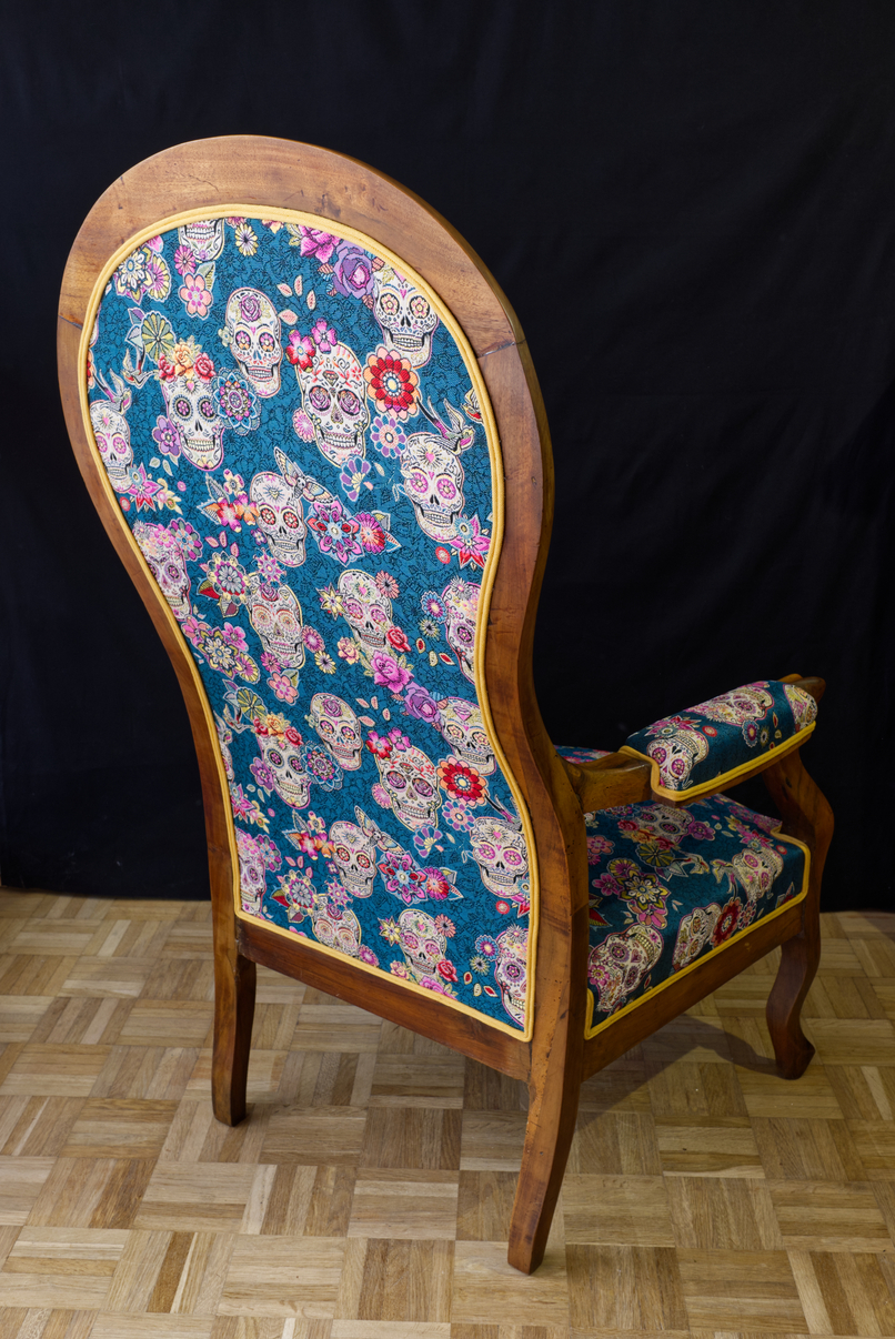Arrière du fauteuil Voltaire en tissu calaveras et fleurs sur fond bleu canard